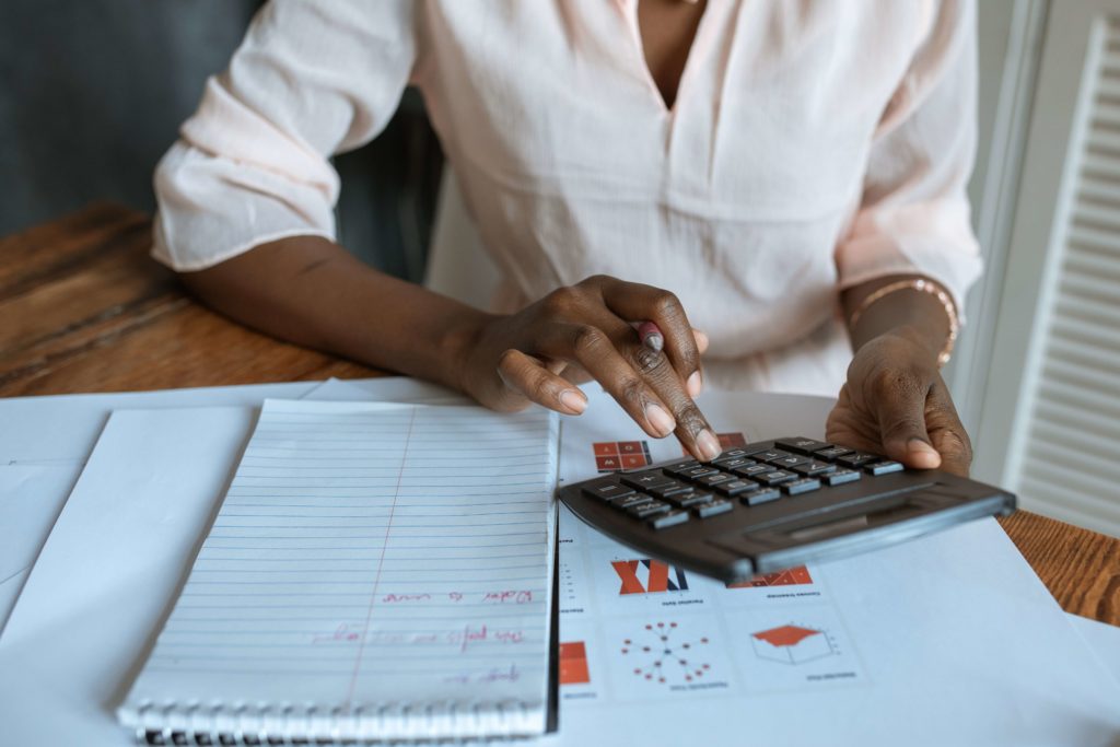 Mulher com uma calculadora sendo responsável por uma relação ilustrativa para a viabilidade financeira de projetos